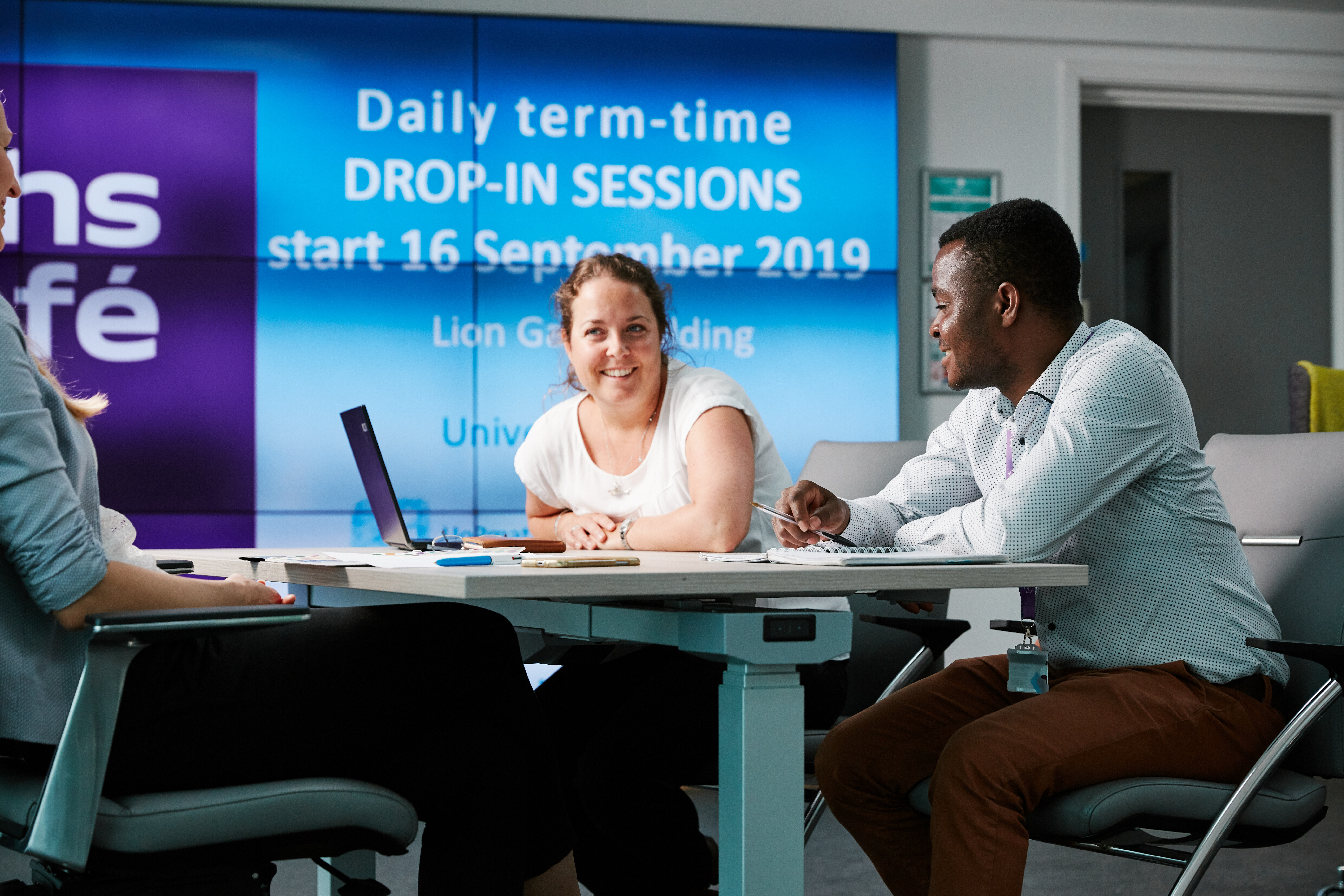 Three people at a communal desk