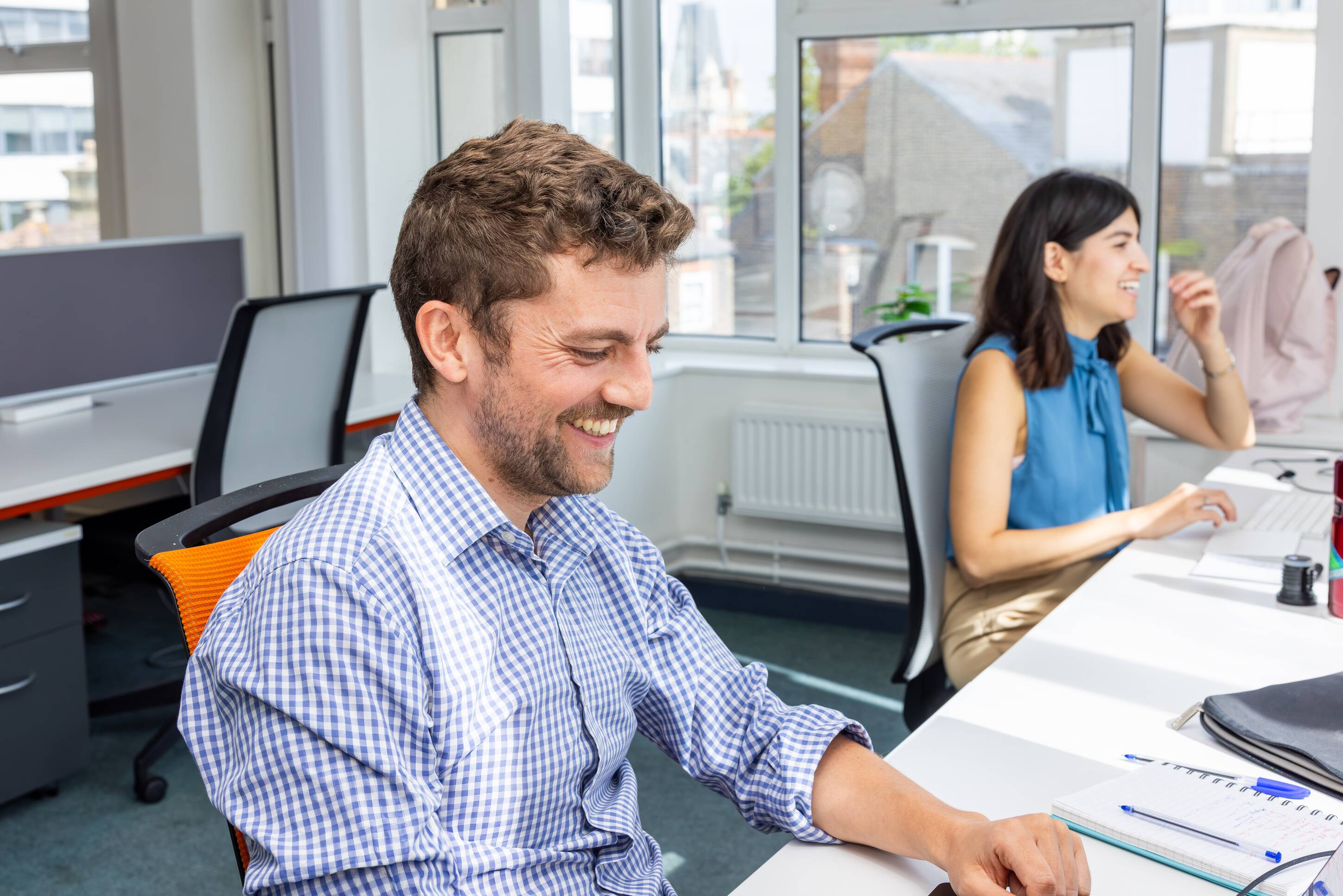 Two people sat at two desks next to each other