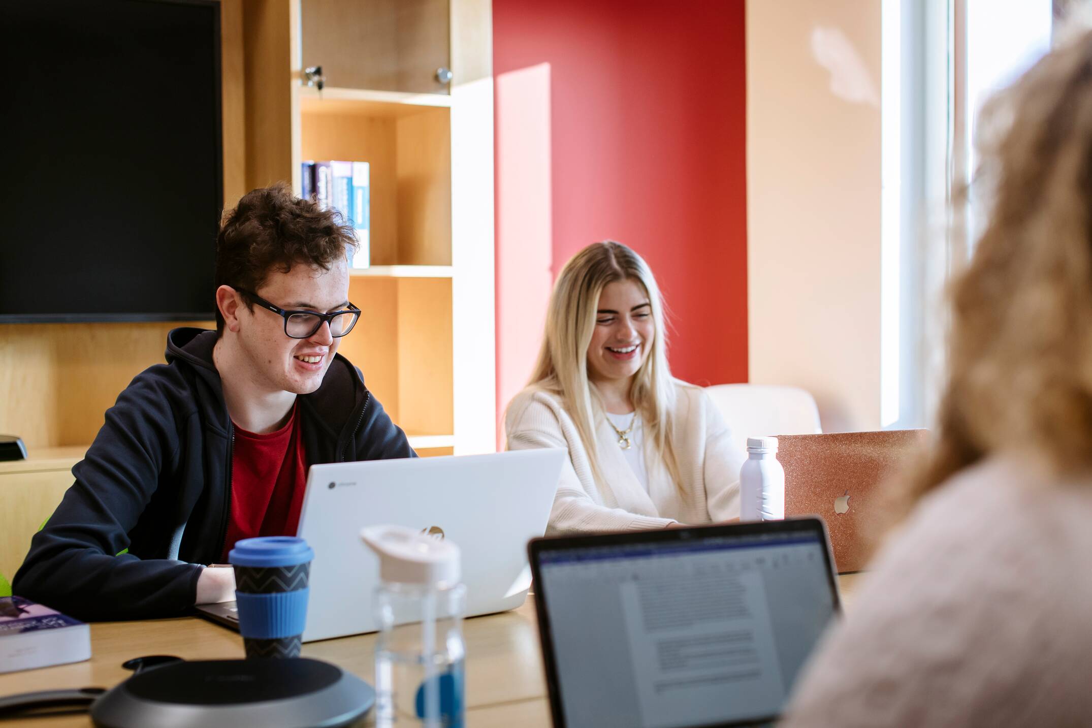 Three students working at computers at desks